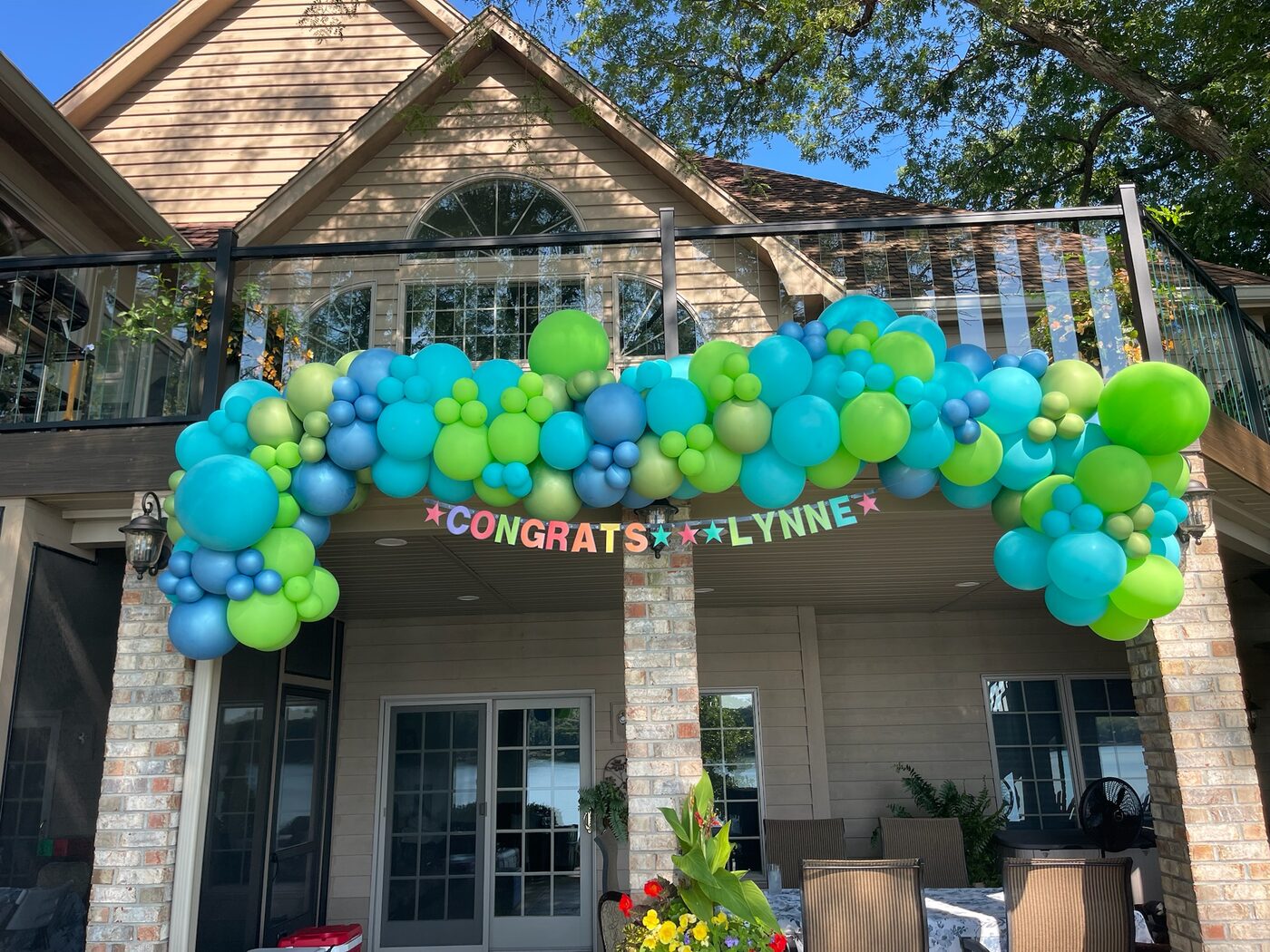 Bright balloon garland installed outside for a graduation celebration