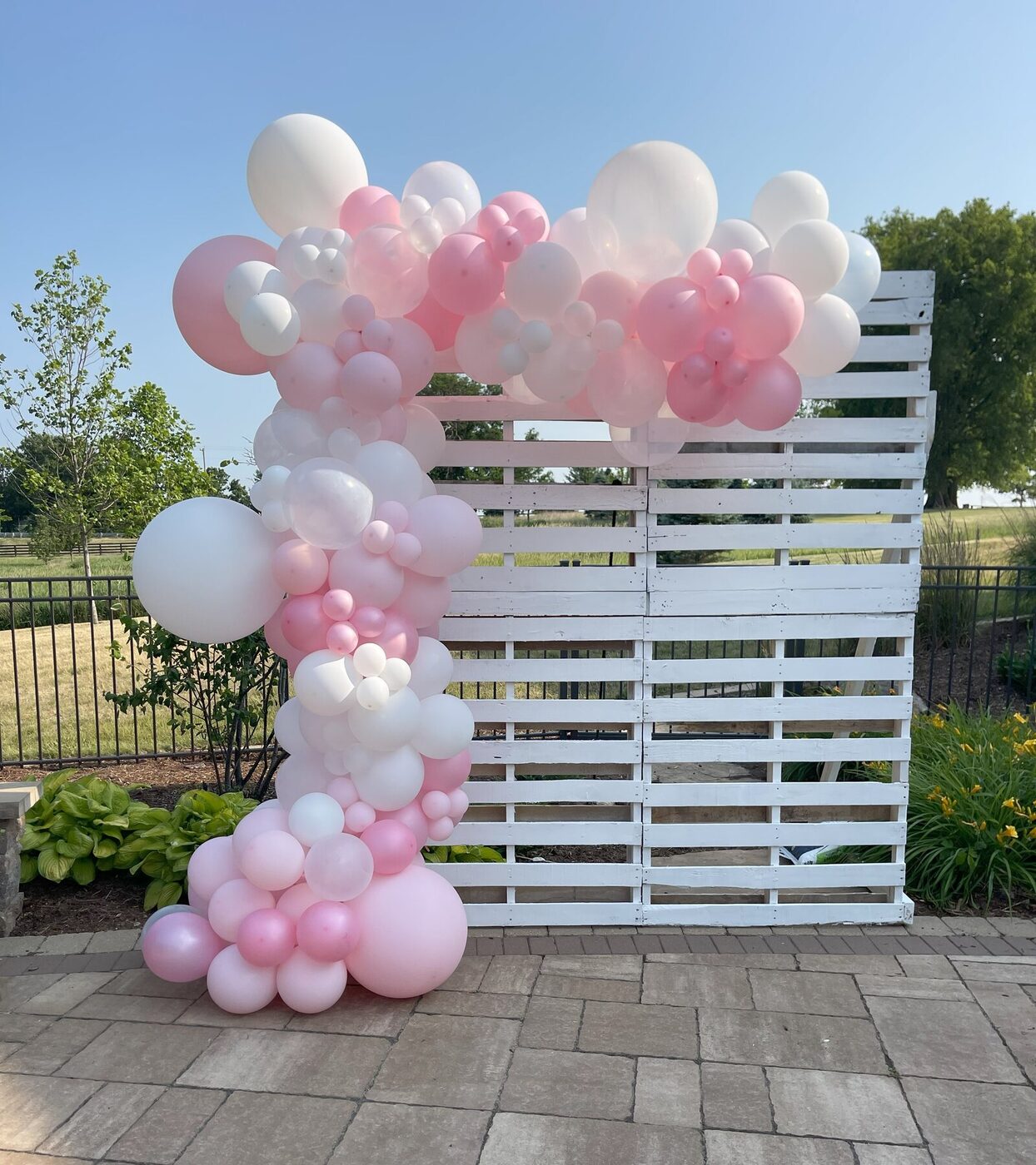 Soft pink and white organic balloon garland on an outdoor backdrop